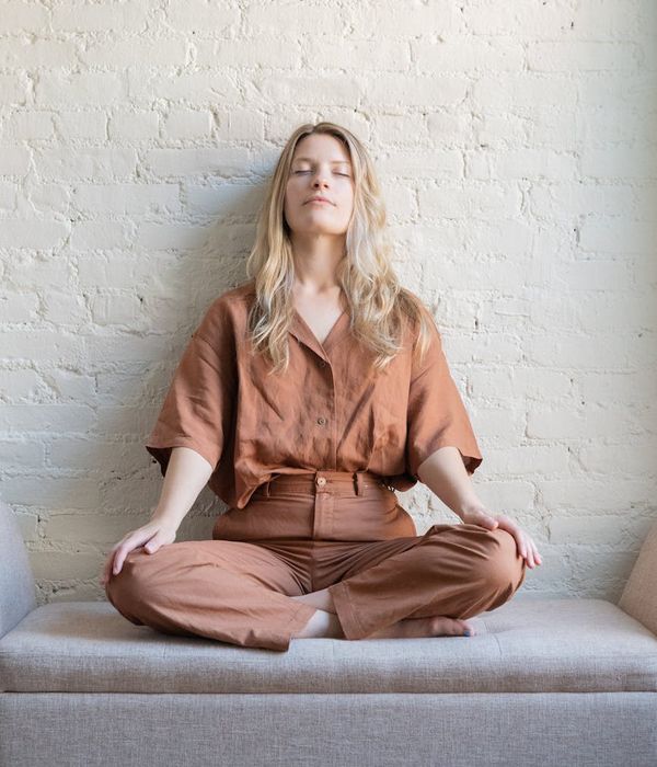 A serene pregnant woman meditating with her eyes closed in a bright room.